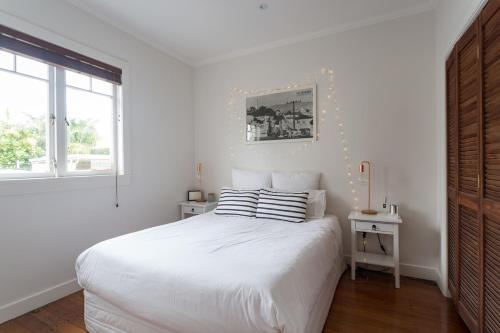 a white bedroom with a bed and a window at Kohimarama Beach 2 Bedroom Charmer in Auckland