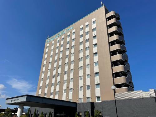 a large hotel building with a blue sky in the background at Hotel Route-Inn Hita Ekimae in Hita