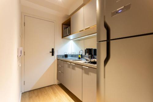 a kitchen with white cabinets and a refrigerator at Nik Perdizes in Sao Paulo