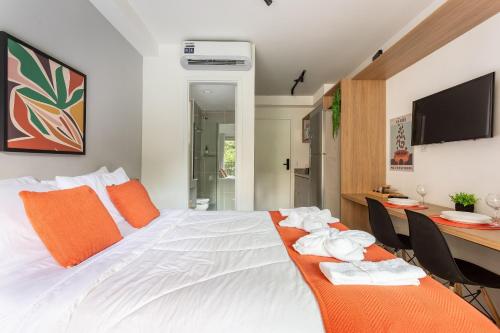 a bedroom with a bed with orange pillows and a desk at Nik Perdizes in Sao Paulo