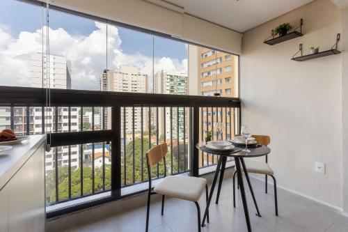 a kitchen with a table and chairs and a large window at Nik Perdizes in Sao Paulo
