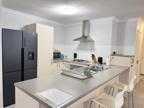 a kitchen with a sink and a refrigerator at Blissful Modern Home in Perth