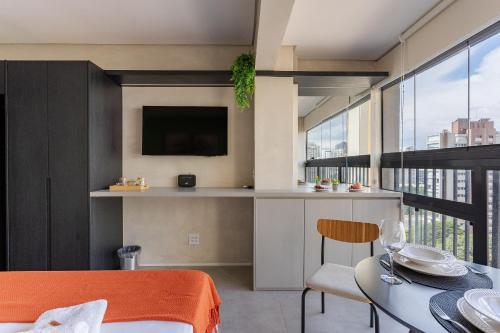 a room with a table and a tv and a balcony at Nik Perdizes in Sao Paulo