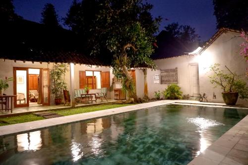 a swimming pool in front of a house at night at D'omah Yogya Hotel in Yogyakarta