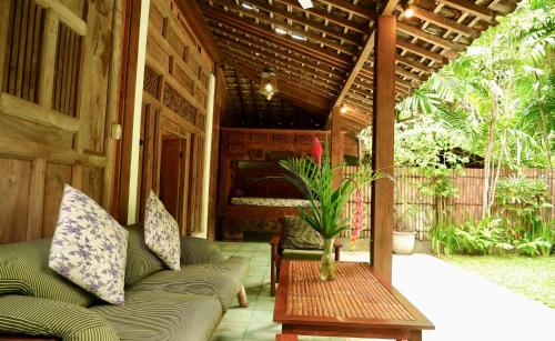 a porch with a couch and a table at D'omah Yogya Hotel in Yogyakarta
