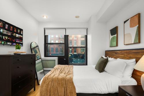 a bedroom with a bed and a dresser and windows at Stylish 2BR Apartment in the Heart of East Village in New York
