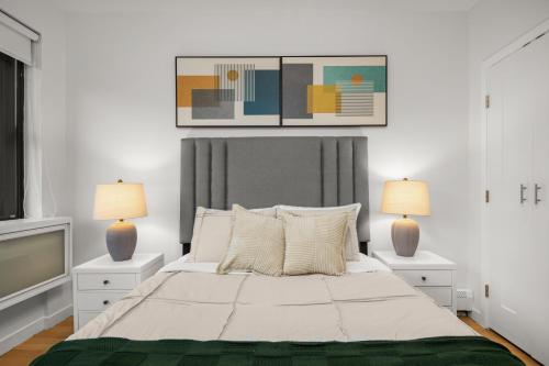 a white bedroom with a large bed with two lamps at Stylish 2BR Apartment in the Heart of East Village in New York