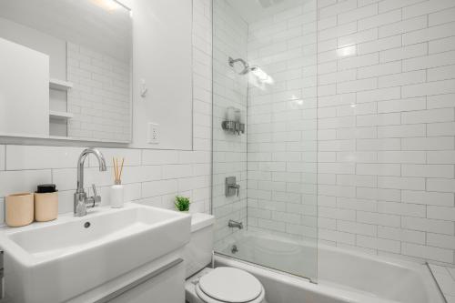 a white bathroom with a sink and a toilet at Stylish 2BR Apartment in the Heart of East Village in New York