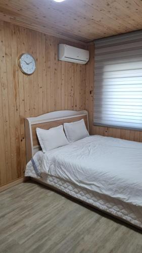 a bedroom with a bed and a clock on the wall at Happy Stay in Gyeongju