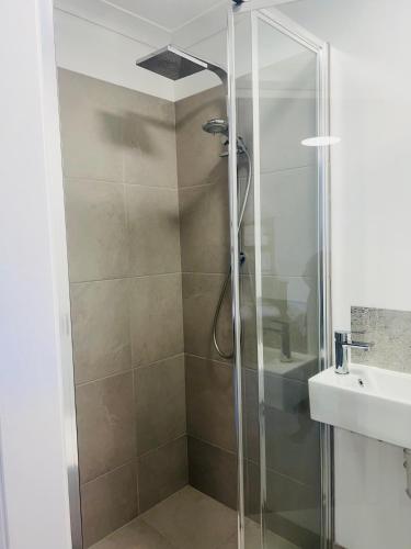a shower with a glass door next to a sink at Bird Paradise In Bush setting in Bendigo