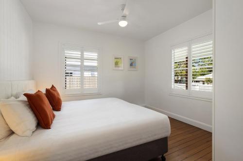 a white bedroom with a bed and two windows at Sunnyside On Burns - Central,Farmers Market, Beach in Byron Bay