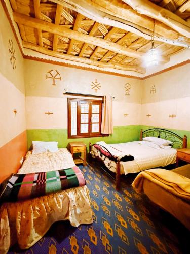 two beds in a room with green walls and wooden ceilings at DAR Moha dades in Aït Ougliff