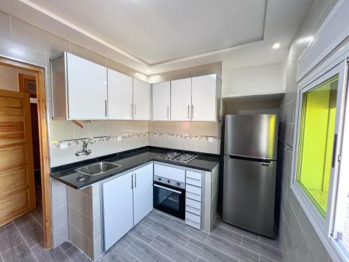 a kitchen with white cabinets and a stainless steel refrigerator at Visit Chamal - Costa Midnight in Oued Laou