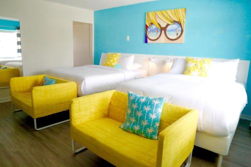 a hotel room with two beds and a yellow chair at Fortuna in Fort Lauderdale