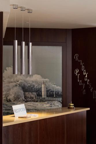 a reception counter with a painting of a lighthouse at Hotel Ribadesella Playa in Ribadesella
