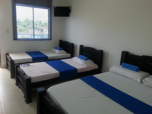 Habitación con 3 camas con sábanas azules y blancas. en Hotel Katylú, en Tolú