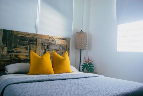 a bedroom with a bed with yellow pillows at Casa Sofía Wabi Sabi Apt with Rooftop, Walk to Beach in Luquillo