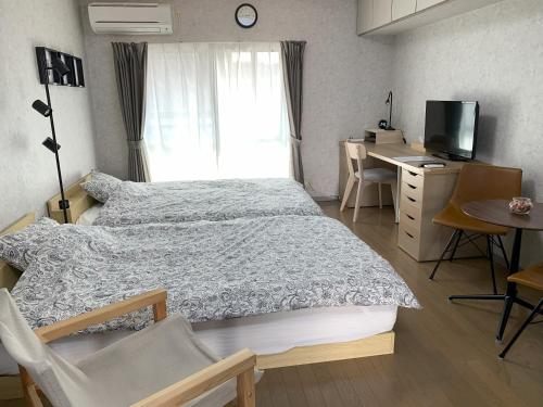 a bedroom with a bed and a desk and a television at あびこハウス ABIKO House in Osaka