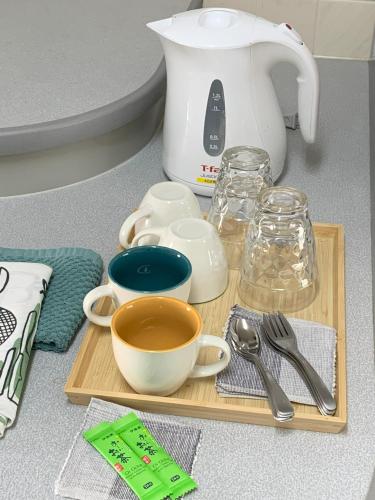 a cutting board with bowls and cups and a tea kettle at あびこハウス ABIKO House in Osaka