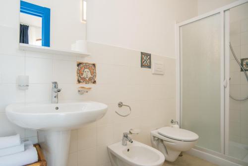 a white bathroom with a sink and a toilet at B&B Villa Ziella in Portopalo