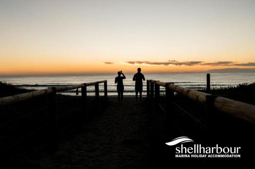 two people standing on the beach at sunset at Seaside Village Retreat in Shellharbour