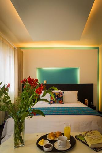 a bedroom with a bed and a table with a tray of food at Wakapunku Boutique Hotel in Cusco