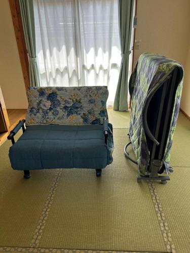 a couch with a pillow and a stroller in front of a window at Onna yuntaku-SEVEN Hotels and Resorts- in Onna