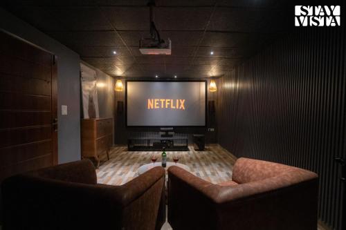 Zimmer mit 2 Stühlen und einem Flachbild-TV in der Unterkunft StayVista at Alpine Bliss - Home Theatre, Bonfire in Masuri