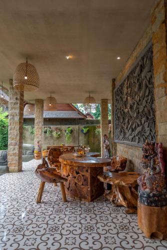 a room with a table and benches and a wall at Hoshi Jungle Resort in Tegalalang
