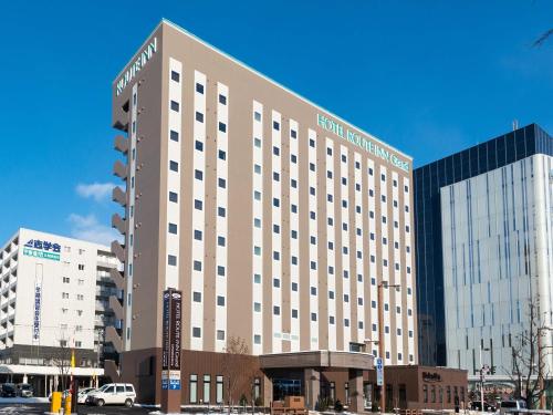 a large hotel building in front of a parking lot at Hotel Route Inn Grand Kitami Ekimae in Kitami