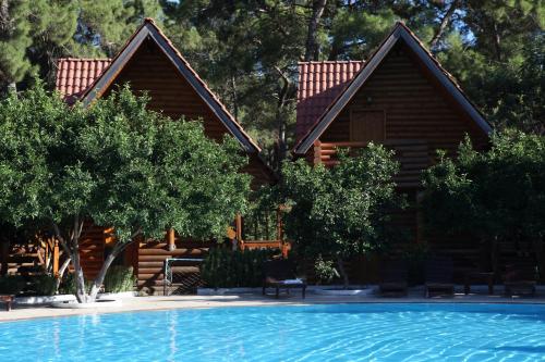 a log cabin with a swimming pool in front of a house at Woodline Hotel in Kemer