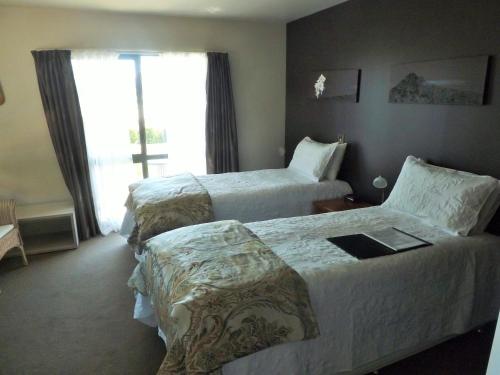 a hotel room with two beds and a window at Hosts on the Coast The Harbourview Tairua in Tairua