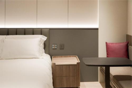 a bedroom with a bed and a table and a desk at Talmud Hotel Classic Taiwan Boulevard in Taichung