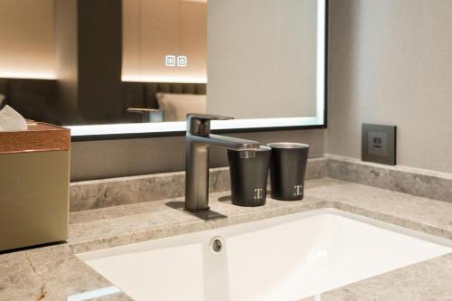 a bathroom sink with a faucet and two trash cans at Talmud Hotel Classic Taiwan Boulevard in Taichung