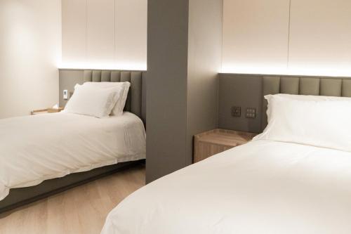 a bedroom with two beds with white sheets at Talmud Hotel Classic Taiwan Boulevard in Taichung