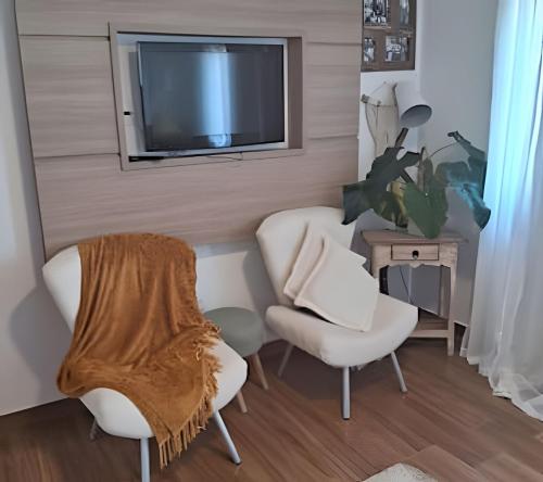 a living room with two chairs and a flat screen tv at Casa paradisíaca em São Pedro da Aldeia RJ in São Pedro da Aldeia
