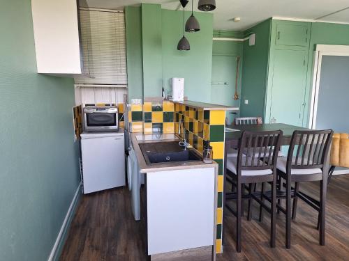 une cuisine avec un évier et un comptoir avec des chaises dans l'établissement Studio cosy à Royan - 21m² pour 2 personnes - FR-1-550-92, à Royan