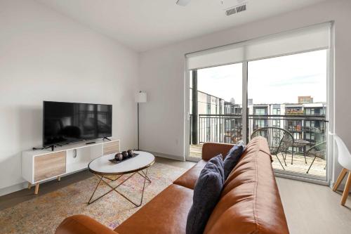 a living room with a couch and a tv at Stunning Nulu 1BR CozySuites 10 in Louisville