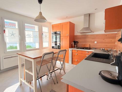 une cuisine avec des armoires en bois et une table et des chaises dans l'établissement Charmante maison de village à Saint-Pierre-d'Oléron, idéale pour 4 personnes - FR-1-778-52, à Saint-Pierre-dʼOléron