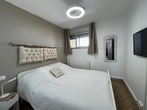 une chambre avec un lit blanc et une télévision dans l'établissement Deux pièces avec vue sur canal et parking privé à Sète - FR-1-338-616, à Sète