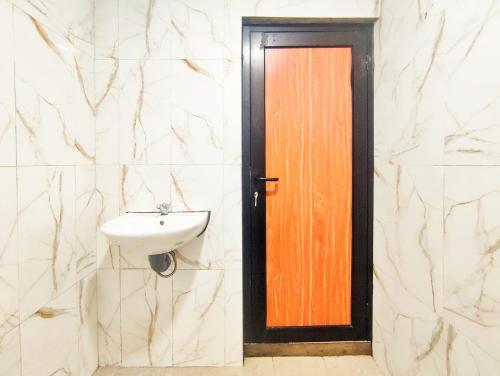 a bathroom with a sink and a wooden door at Napoleon Hills Tambi Tea Gardens View RedPartner in Kejajar