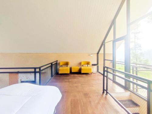 a bedroom with two yellow chairs on a balcony at Napoleon Hills Tambi Tea Gardens View RedPartner in Kejajar