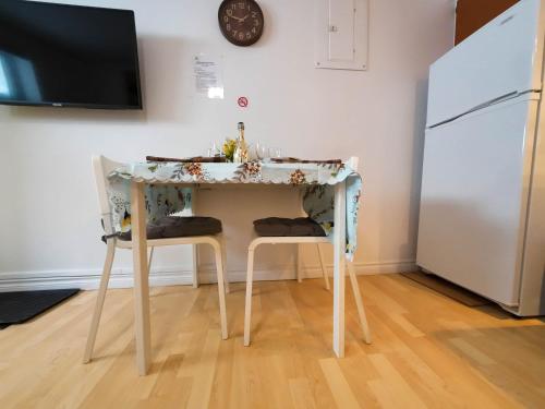 a kitchen table with two chairs and a white refrigerator at Logis des Prodiges - Le 773 in Rouyn