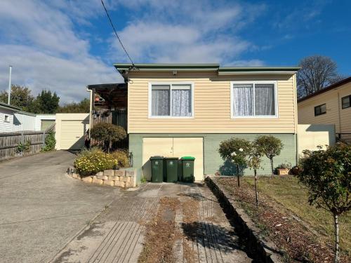 a house with two green trash cans in the driveway at Coleman Comfort Hub - close to City&Air port in Moonah