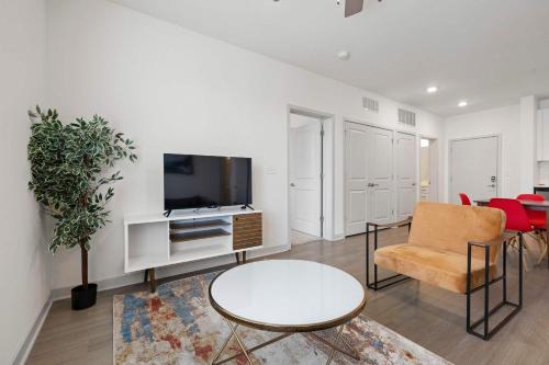 a living room with a tv and a couch and a table at Modern Nulu 2BR CozySuites 10 in Louisville