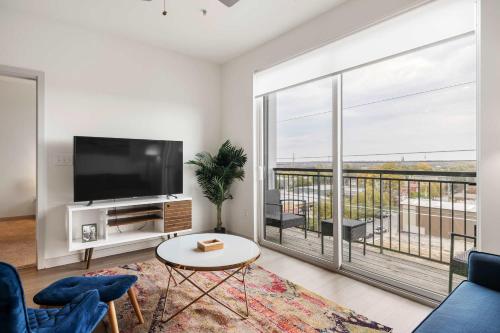 a living room with a tv and a large window at Modern Nulu 2BR CozySuites 07 in Louisville