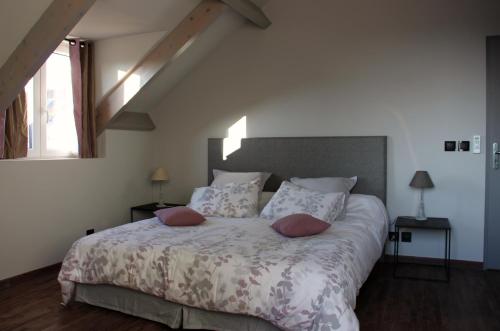 a bedroom with a large bed with two pillows at L'Alisier Chantant in Bourron-Marlotte