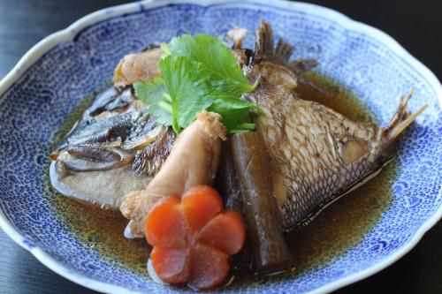 a blue plate of food with fish and vegetables at 坂本屋旅館 in Kyotango