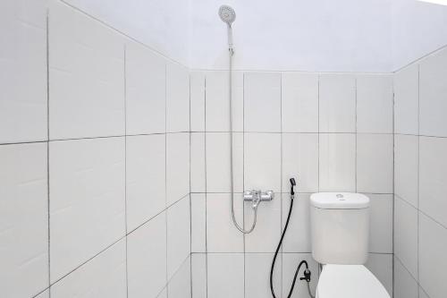 a white bathroom with a shower with a toilet at RedDoorz Syariah Near Alun-Alun Kudus in Kudus