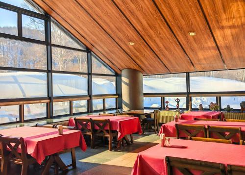 a restaurant with red tables and chairs and windows at Berjaya Hakkoda Ski Resort in Aomori